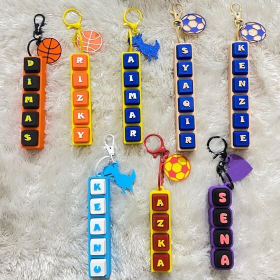 Delapan gantungan huruf balok warna-warni dengan charm bola
