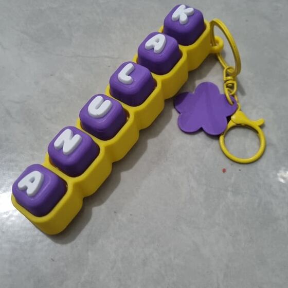 Fidget clicker nama Anjuka ungu kuning dengan charm bunga