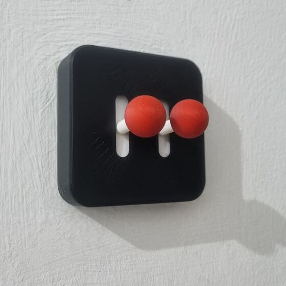Cover saklar lampu hitam dengan dua tombol merah, terpasang di dinding