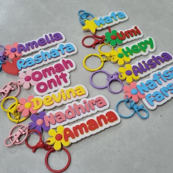 Deretan gantungan kunci nama warna-warni dengan charm bunga